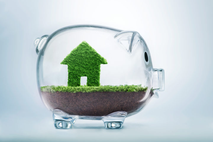 Save money and energy green grass house inside a glass piggy bank shows how you can save money by saving energy