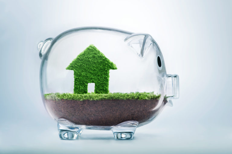 green grass house inside a glass piggy bank shows how you can save money by saving energy